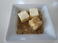 小さなお皿にすりごまとキューブ状のクリームチーズを入れ、すりごまをクリームチーズの表面にたっぷりまぶします。<br />
