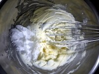 バターをクリーム状に白っぽくなるまで、泡立て器で撹拌します。砂糖を加え、ざらざらがなくなり、全体がクリーム状になるまで、さらに撹拌します。