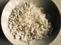 ココナッツロングを水でしめらせてから、白玉粉、砂糖、塩と混ぜ合わせます。<br />