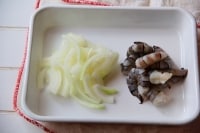 里芋は洗って耐熱皿にのせ電子レンジで約4分加熱し、皮をむいて食べやすい大きさに切る。えびは殻をむき、背ワタを除く。たまねぎは薄切りにする。<br />