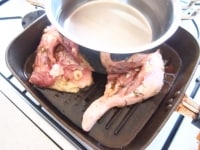 鶏肉の上に水を張った鍋（重石）をのせ、中火にかけてしっかり焼き色をつけます。片面が焼けたら裏返し、塩、こしょうをします。裏面も同様に焼きます。