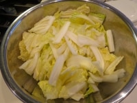 あらかじめ水をしっかり拭いた白菜を5センチ程度の長さに切ってボウルに。茎の部分はさらにそれを1,5センチ幅程度にそぎ切り。葉の部分は5センチ角程度に。適当でかまいません。<br />
