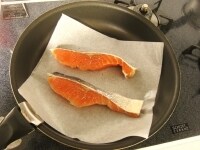フライパンにオーブンシートを広げ、表面の水気を拭き取った鮭を並べて中火にかけます。両面がきつね色になるまでソテーします。