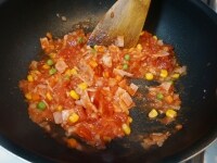 フライパンにオリーブオイルとにんにくを加えて熱し、香りが立ったら、玉ねぎ、ベーコン、ミックスベジタブルを炒め、トマト缶を加えます。