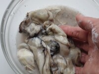 牡蠣をボウルに入れ、片栗粉をまぶし<br />
水を1カップほど（分量外）入れてよく混ぜ<br />
ごみを流すように4~5回すすぎ洗いをする。<br />