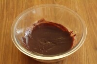 耐熱ボウルに細かく刻んだチョコレート、バターを入れ、湯煎にかけて溶かします。<br />