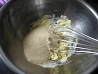 室温に戻したバターをクリーム状に白っぽくなるまで混ぜ、きび砂糖を加え、さらにクリーム状になるまで全体を泡立て器でよく混ぜます。