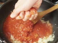 フライパンにサラダ油を熱して、ニンニクと玉ねぎを炒めます。トマト缶を手でつぶしながら加えたあと、厚揚げも加えて、3分ほど煮込みます。