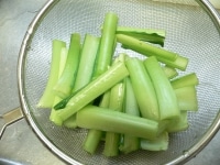 小松菜は1本ずつ外して綺麗に洗い、葉と茎に切り分け、茎の根元を浅く切り落として5cm長さに切る。<br />