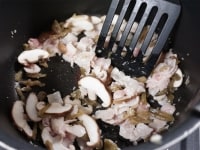 別の鍋にごま油とにんにく、生姜を熱し、香りが立ったら、豚肉を加え、色が変わるまで炒めます。しいたけとザーサイも加えて炒め、全体に油が回ったら、水と鶏ガラスープの素を加えます。