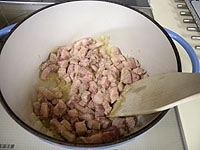 豚バラ肉は塊を使い粗みじん切りにします。鍋にオリーブオイルとニンニクを入れ中火にかけ、さっと炒めたら玉ねぎを加え炒めます。次に豚バラ肉を加え炒めます。<br />