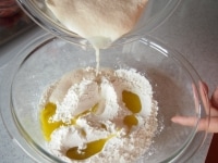 ボウルに２回振るった強力粉と塩、オリーブオイルを入れ、そこに２）を加えて混ぜ合わせます。