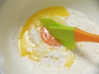 ボウルにホットケーキミックスを入れ、一カ所にまとめて卵、牛乳、溶かしバターを入れ、ゴムベラでまずは液体部分を混ぜる。<br />