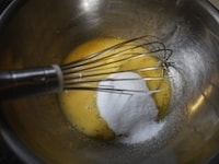 ときほぐした卵にグラニュー糖を加え、グラニュー糖のざらざらがなくなり、全体がもったりした状態になるまで、泡立て器でよく混ぜます。