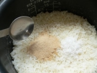 炊飯器でご飯を炊いて、塩、砂糖を入れ、酢を回し入れる。<br />