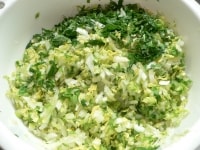 白菜と小松菜はみじん切りにし、塩を２つまみふりかけてまぶしてしばらく置き、布巾で包んで水気を絞る。絞り汁をとっておく。ねぎはみじん切りにして水気を絞る。<br />