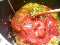 水煮トマトを手で握りつぶして入れ、ピクルスを入れ、水、スープの素、塩を入れて7～8分煮る。<br />
