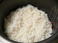 ベーコンを敷いた上に米をあけ、2合の線まで牛乳を入れ、酒（又は白ワイン）を入れる。<br />