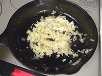 玉ねぎとニンニクはみじん切りにします。フライパンにサラダ油を入れ中火にかけ、ニンニクと玉ねぎをしんなりするまで炒めます。 <br />