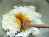 ボールにご飯と卵を入れて、ヘラかスプーンで切るように混ぜて、ご飯に卵をからめる。<br />