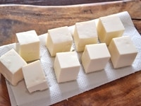 豆腐は、3cm角ほどの立方体に切り、キッチンペーパーの上などにのせて、軽く水気を切っておきます。<br />