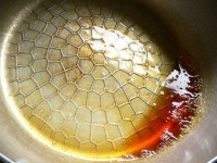 鍋に砂糖と水を入れて加熱し、色がついてきたら鍋を回して混ぜて、全体が薄茶色になったところでぬるま湯をジュッと入れ、急いで鍋を回して均一に混ぜる。<br />