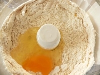 フードプロセッサーに薄力粉と砂糖を入れて数秒混ぜ、角切りにしたバターを入れて混ぜて粉状にして、バニラエッセンスと卵を入れて混ぜる。<br />
<br />