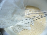 ボウルに卵と牛乳を入れて泡だて器で混ぜ、ホットケーキミックスを入れて混ぜる。<br />