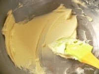 室温に戻したバターを、クリーム状になるまでゴムベラで練る。砂糖を入れ、泡立て器に持ち替えて、白っぽくふわふわになるまで混ぜる。卵を1個ずつ加え、その都度しっかりと混ぜる。<br />