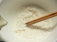 箸で混ぜながら水を加えていき、粉全体に水分を行きわたらせる。<br />
