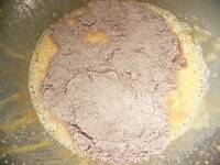 ふるっておいたココアと薄力粉を広げ入れ、ダマが残らないよう、ゴムベラでややしっかりめに混ぜる。<br />