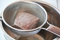 鍋に牛肉とかぶるくらいの水を入れて中火にかける。煮立ったらそのまま約5分加熱してアクを取り、ザルにあげる。<br />