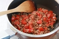 鍋にオリーブオイルを熱し、ひき肉を入れてパラパラになるまでしっかりと炒める。ニンニク、トマトを入れて炒め合わせる。<br />
&nbsp;