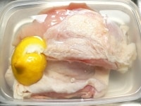 塩水に鶏肉を沈める。あれば、レモンのヘタや汁を搾った後の皮を一緒に入れ、冷蔵庫で2時間(～12時間以内)漬け置く。<br />