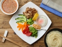 うどんと付け添え野菜を盛り付け、つゆを添える