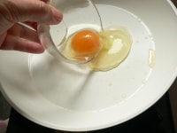 （1）のフライパンの汚れを拭いて火にかけ、油をひいて、フライパンが熱くなったところで卵を割り入れる。<br />