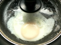油を熱して卵を落とし、水を回し入れたらすぐに蓋をして普通に焼いて火を止め、蓋をしたまま2～3分ほど蒸らす。<br />