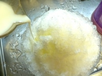 かき氷器で氷を削ったら、手の平で軽く押さえて固め、ミルクシロップを回しかける。<br />