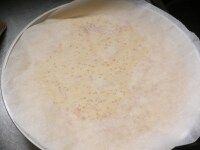 （1）で切っておいたオーブンペーパーをかぶせる。平らな鍋蓋をかぶせ、一気に裏返して蓋で受け止めて、ペーパー側を下にしてフライパンに戻す。<br />
