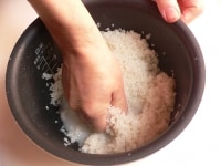 水を少し入れ、手で米を握っては放しを10回ほど繰り返す。<br />