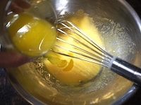 卵を白身と黄身に分けます。卵黄にグラニュー糖40gを加えて、白っぽくもったりするまで泡立て器で撹拌します。1000wの電子レンジに40秒かけて溶かしたバターを加え、よく混ぜます。