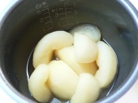 スイッチが切れたらできあがり。梨を別の容器に移し、煮汁（シロップ）をかけて冷ます。<br />