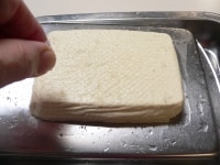 ペーパータオルを外し、豆腐の両面にまんべんなく塩をふる。<br />
<br />
塩は、裏表にひとつまみ強ずつ。<br />