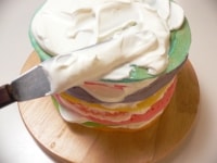生クリームと砂糖とバニラエッセンスを泡だて器で混ぜてホイップクリームを作り、シロップを塗った面に塗って重ねていく。<br />