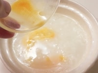 お粥が好みの柔らかさに煮えているのを確認し、溶き卵を回し入れる。<br />