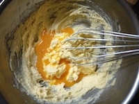 ときほぐした卵を2～3回に分けて加え、その都度、泡立て器でクリーム状になるまでよく撹拌します。