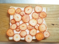 全体にまんべんなくクリームを塗り、輪切りにしたイチゴを敷き詰めるようにして並べる。<br />
<br />
※このとき、食パンからいちごがはみ出るように並べたほうが、切ったときにかわいいです。