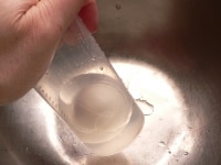 コップにゆで卵と水を1/3カップ入れ、コップの口を手でおさえて、数回振る。<br />