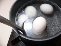 煮立ってきたら、湯からゆでる卵(D、E、F)を1個ずつお玉にのせて、静かに入れていき、ここから10分間ゆでる。<br />