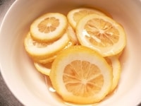 レモンは2mm厚に切って耐熱容器に入れる。はちみつを注ぎ入れ、レモンにまぶしつけるように混ぜ、30分ほど漬けておく。途中で1～2回混ぜる。<br />